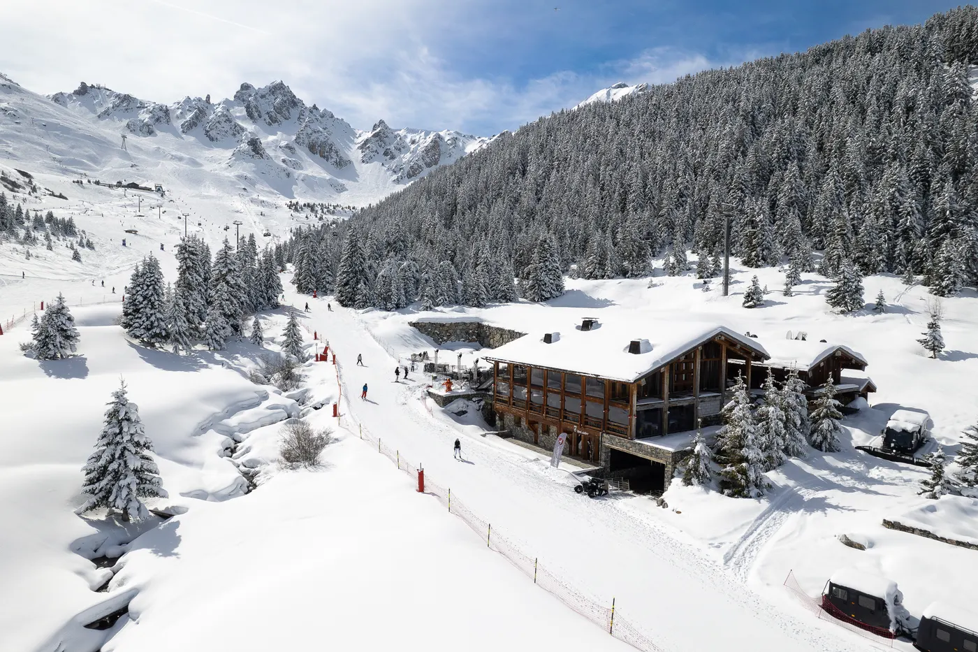 Baïes Après Club ski restaurant surrounded by snowy slopes and pine forests in Courchevel.