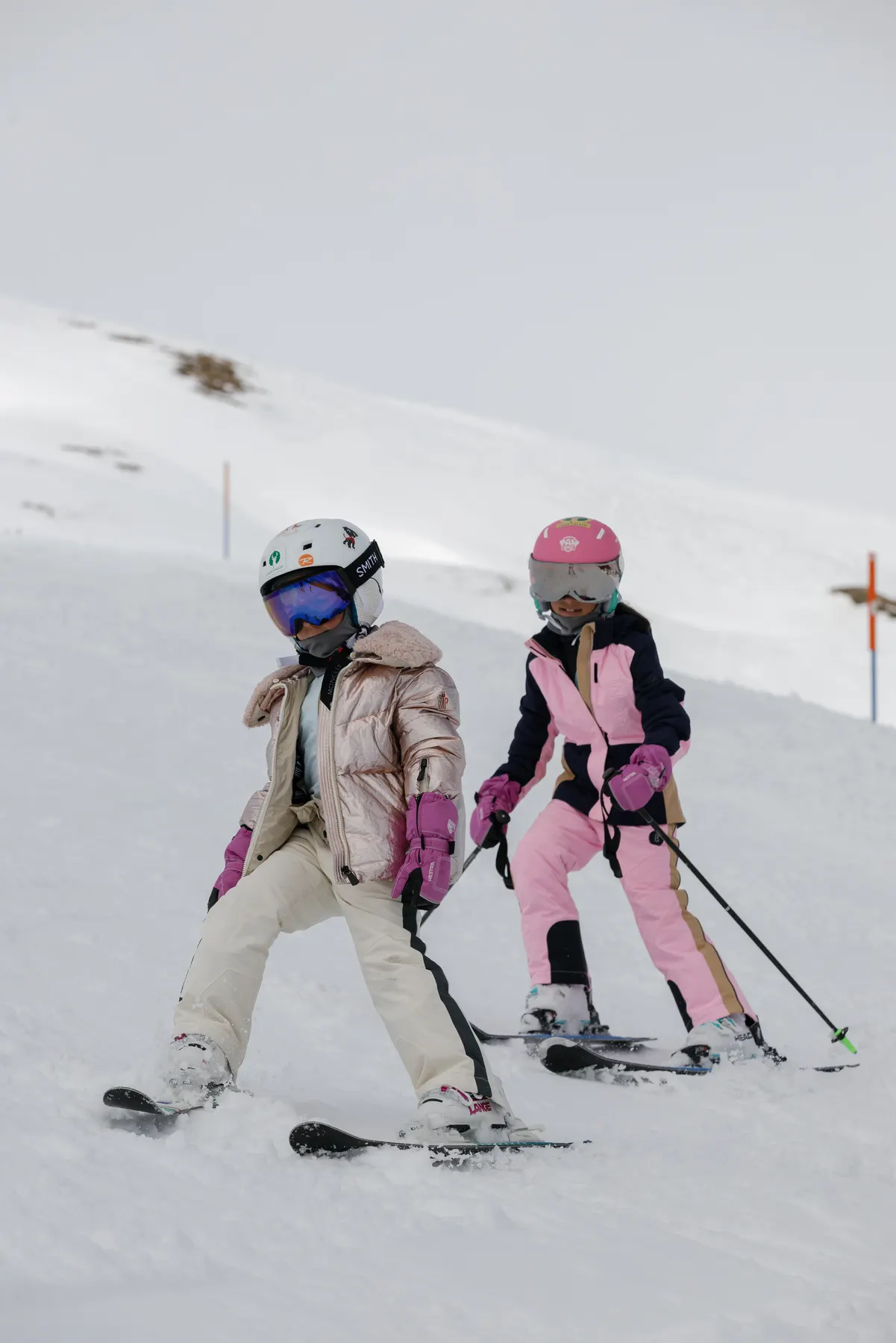 Two children skiing together during a family ski holiday in Courchevel, wearing Moncler and Bogner ski wear.