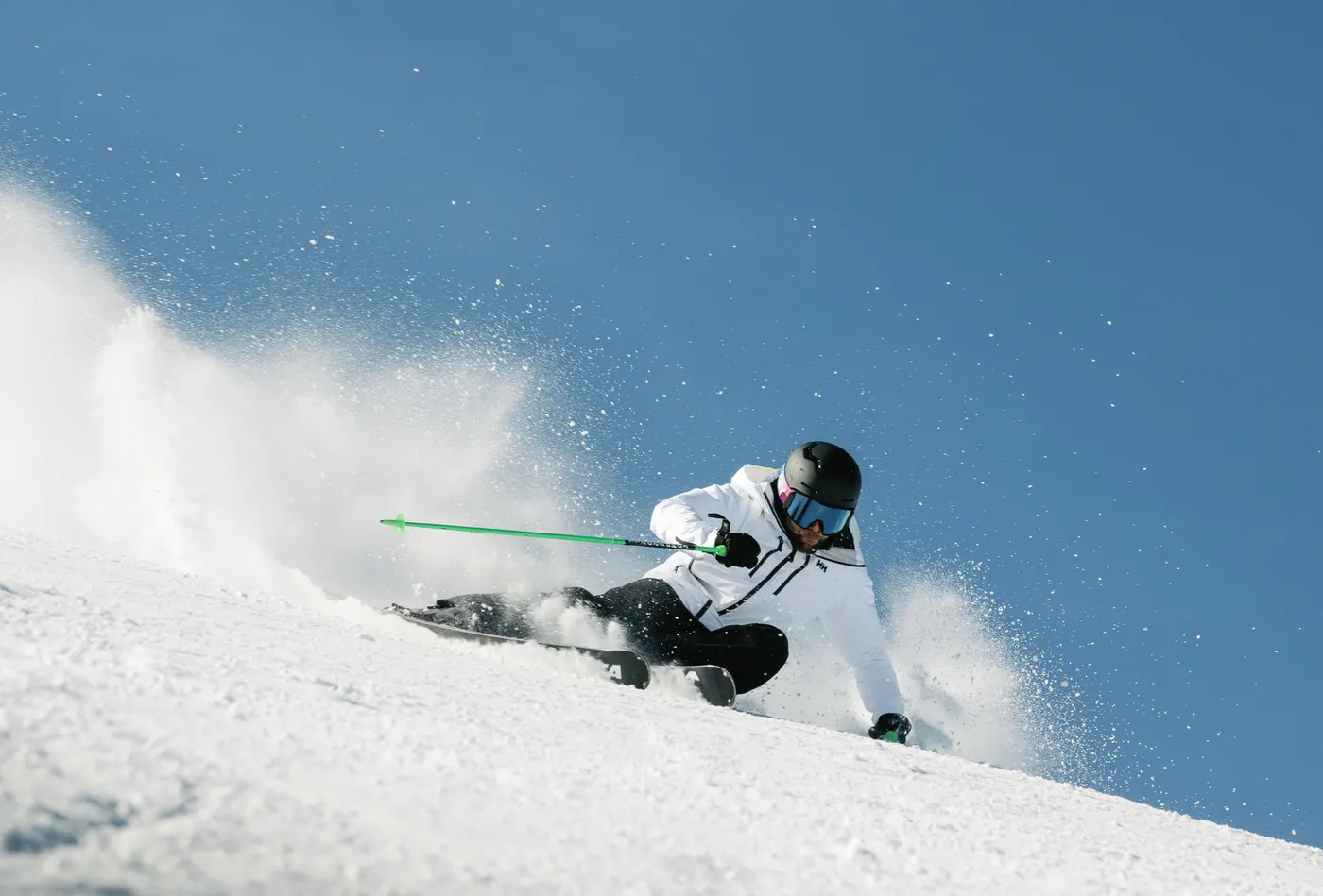 Skier carving through fresh snow in Courchevel wearing a Helly Hansen ski jacket.